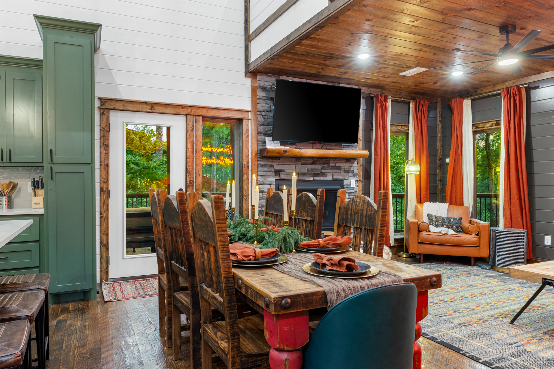 Dining table set with rust napkins, brass candelabras, and an evergreen centerpiece in front of the Oklahoma mural