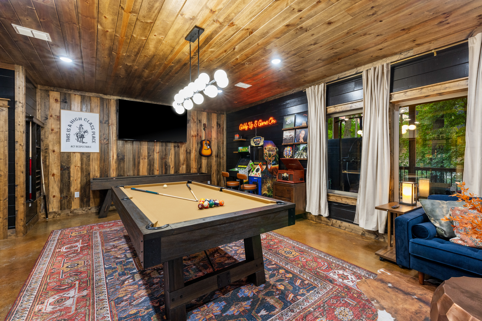 Lazy Lariat saloon-themed game room after — pool table, dartboard, vintage neon Saddle Up sign