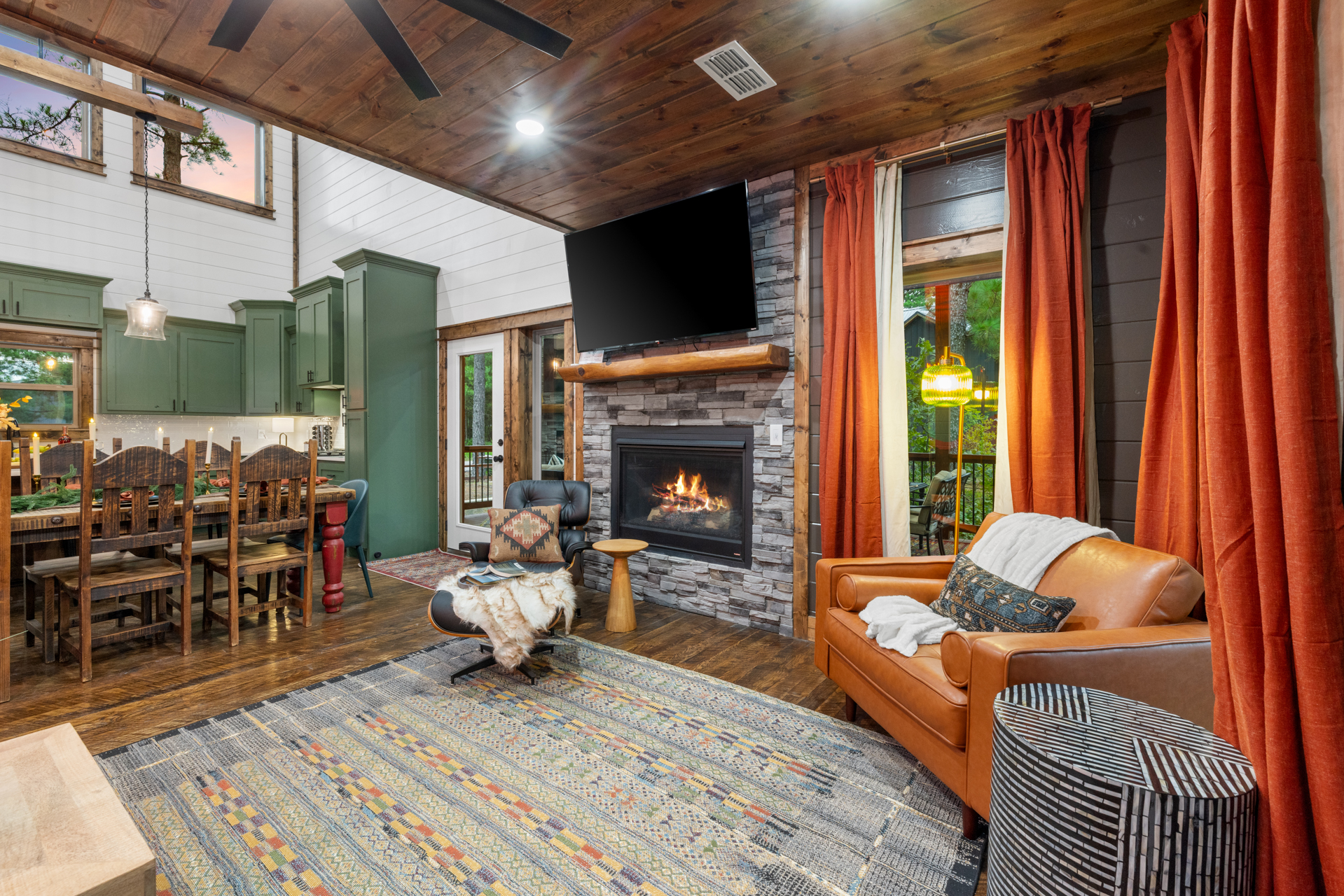 Living-and-dining area looking toward the sage-cabinet kitchen, with the fireplace on the right and the dining table dressed for service
