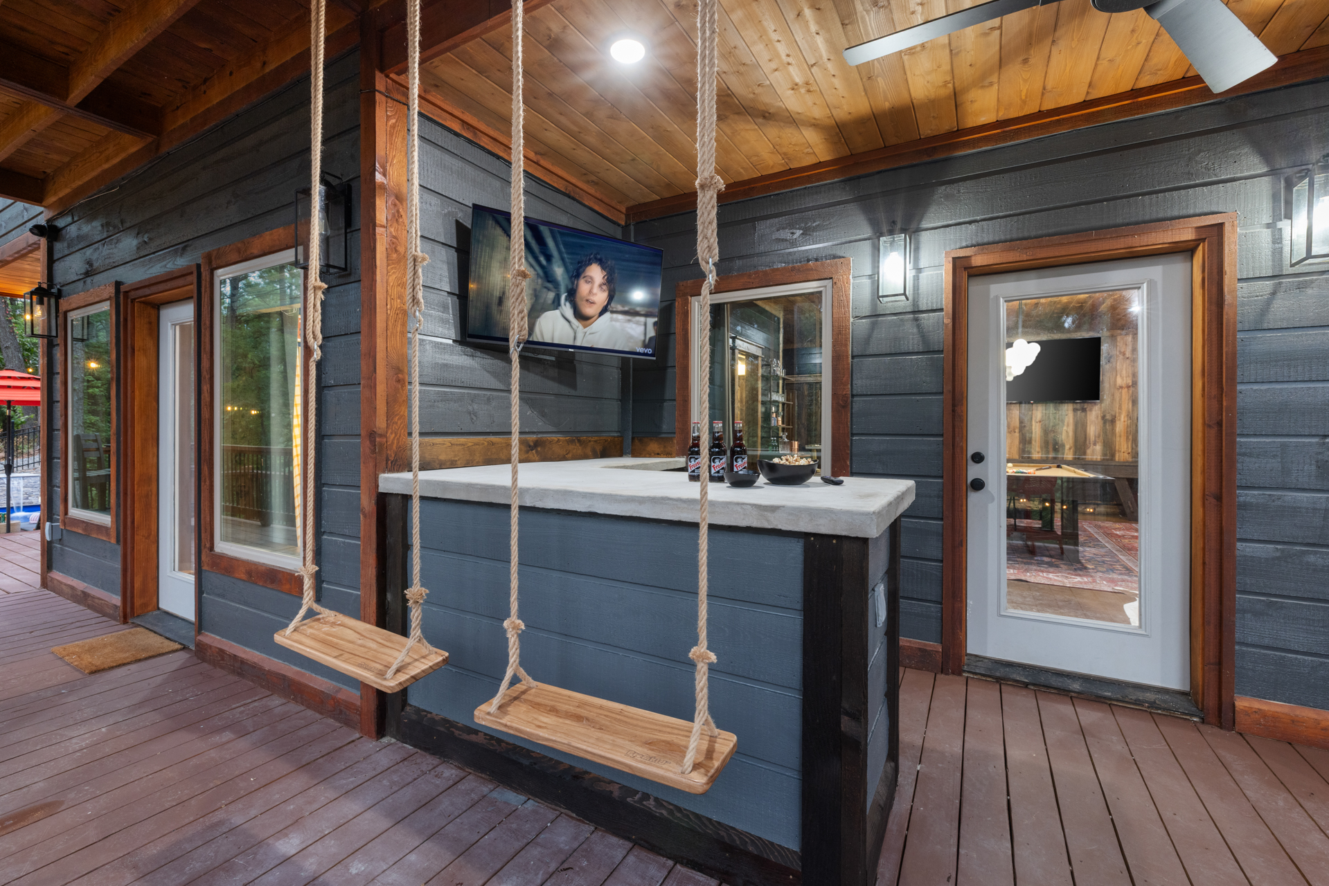 Outdoor concrete swing bar with rope swings, beer bottles, and an outdoor TV