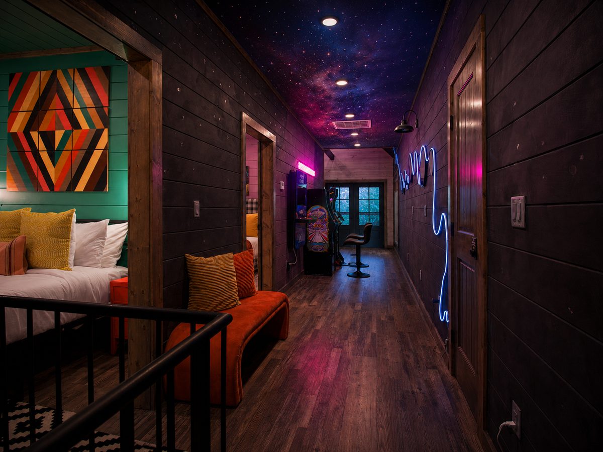 Loft hallway with a galaxy ceiling, neon accent and arcade at Space Cowboy in Hochatown, Oklahoma